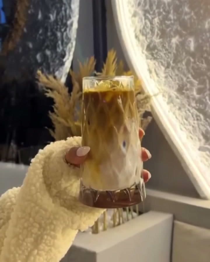 Işıklı aynanın önünde elde tutulan buzlu latte